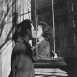 Un homme et une femme s'embrasse derrière une vitre